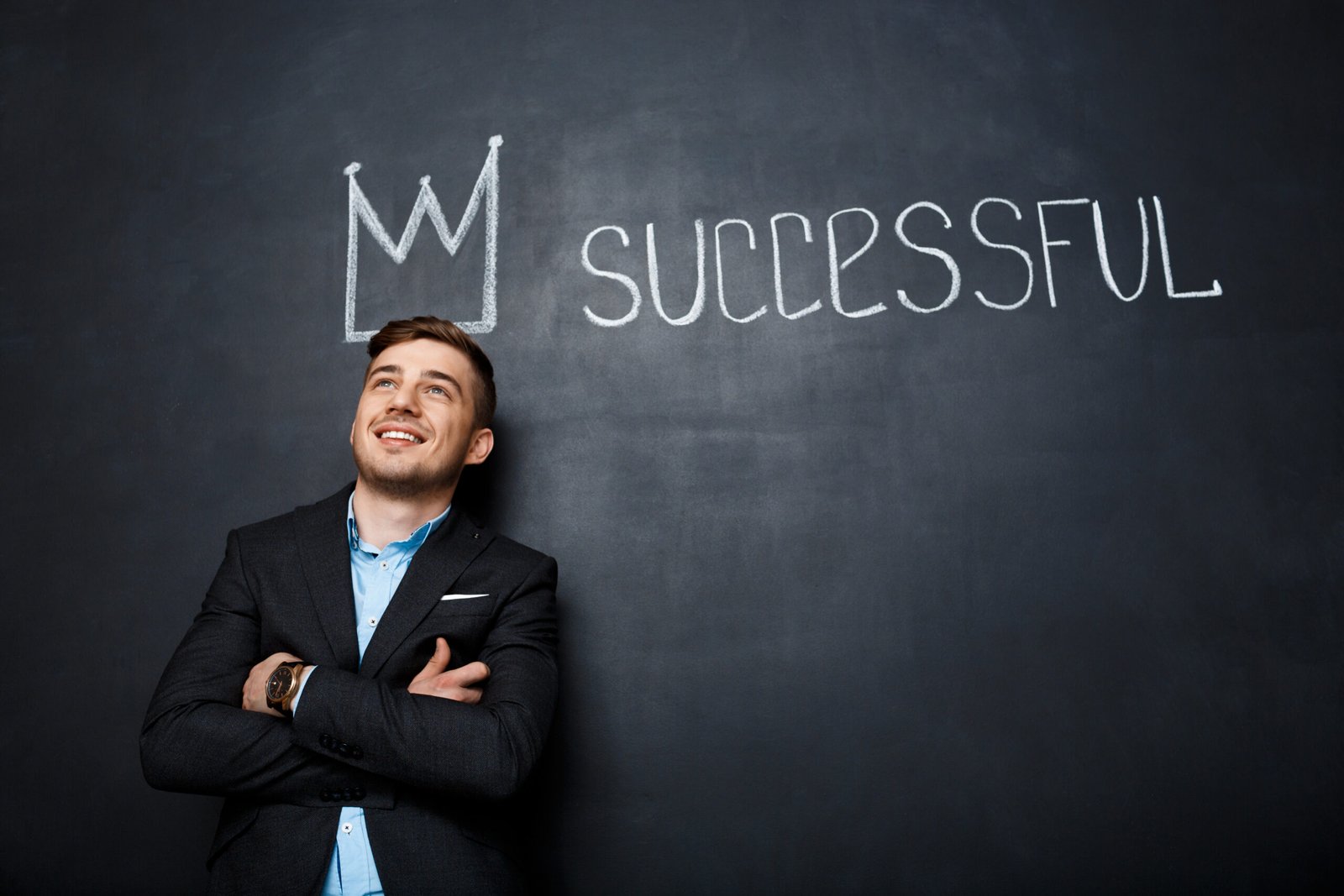 picture of suited, happy, smiling man over blackboard with crown above his and text successful.